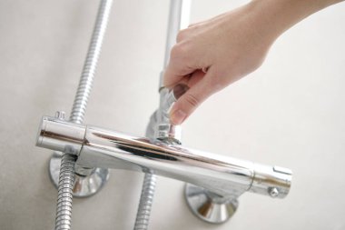 Dişi el duş musluğunu açtı. Banyo içinde modern duş seti. Hijyen kavramı