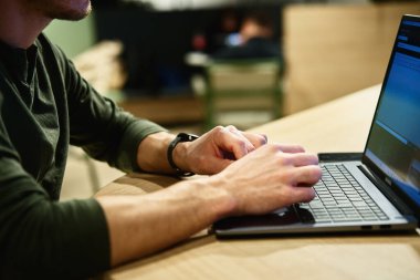 Erkek eller dizüstü bilgisayarda klavye ile yazı yazıyor. Yaklaş. Ofiste dizüstü bilgisayar kullanan bir adam. Çevrim içi iş