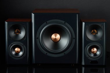 Multimedya ses hoparlörleri. İki uydusu olan ses sistemi ve koyu arkaplanda subwoofer. Müzik dinlemek için müzik sistemi