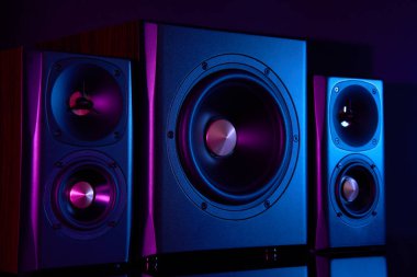 Neon ışıklı multimedya ses hoparlörleri. İki uydulu ses sistemi ve koyu arkaplanda subwoofer..