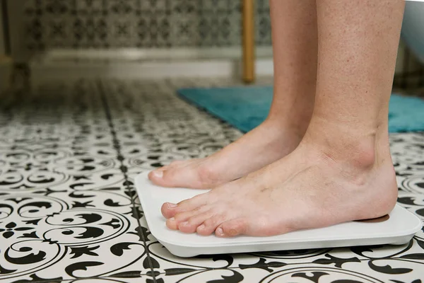 在浴室里 赤脚女人在秤上检查自己的体重 女性在地板上使用数字秤测量自己的体重 — 图库照片