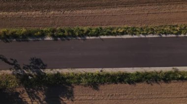 Bisiklet süren adam eğitimi. Bisiklet üniforması ve kask giyen erkek sporcu tarla yakınlarındaki kırsal yolda bisiklet sürüyor..