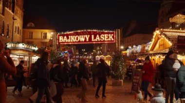 Turistler Wroclaw 'daki ana meydanda yürüyorlar. Wroclaw, Polonya 'daki Noel Fuarı. Gece şehir caddesi, şenlikli süslemeler ve aydınlatılmış ışıklarla dolu. Wroclaw, Polonya - 09 Aralık 2022