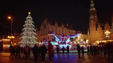 Turistler Wroclaw 'daki ana meydanda yürüyorlar. Wroclaw, Polonya 'daki Noel Fuarı. Gece şehir caddesi, şenlikli süslemeler ve aydınlatılmış ışıklarla dolu. Wroclaw, Polonya - 09 Aralık 2022