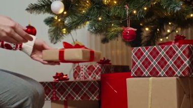 Kadın hediyeler hazırlar, onları Noel ağacının altına koyar. Kış tatili hediyesi. Noel ve Mutlu Yıllar Kutlaması