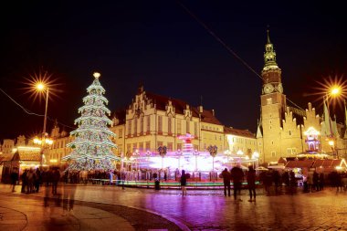 Turistler Wroclaw 'daki ana meydanda yürüyorlar. Wroclaw, Polonya 'daki Noel Fuarı. Gece şehir caddesi, şenlikli süslemeler ve aydınlatılmış ışıklarla dolu. Wroclaw, Polonya - 09 Aralık 2022