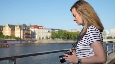Kadın şehir caddesinde fotoğraf çekiyor. Kadın gezgin şehirde kamerayla yürüyor.