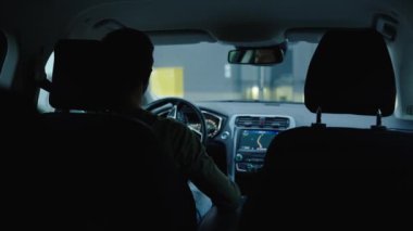 Erkek sürücü evin avlusundaki otoparka park ediyor. Adam arabayı sürüyor, geri geri gidiyor.
