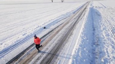 Erkek koşucu kış karlı yolunda koşuyor, yarışmaya hazırlanıyor. Kış koşu egzersizleri. Soğuk dondurucu günde atlet eğitimi