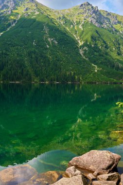Yaz günü güzel göl kenarındaki dağların muhteşem manzarası. Polonya 'daki Tatra Ulusal Parkı. Beş Göl Vadisi 'ndeki Morskie Oko ya da Sea Eye Gölü' nün panoramik manzarası