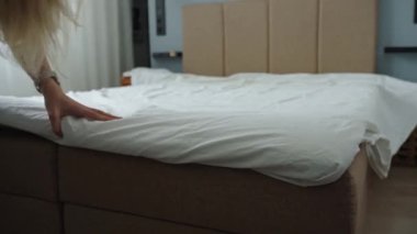 Odada çarşaf değiştiren kadın. Yatak odasında yatak yapan bir kadın. Rutin işler ve ev işleri.