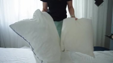 Kadın odada çarşaf değiştiriyor. Yatak odasında yatak yapan bir kadın. Rutin işler ve ev işleri.