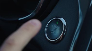 Adam arabadaki motoru çalıştırma düğmesine basıyor. Motor çalıştırılıyor