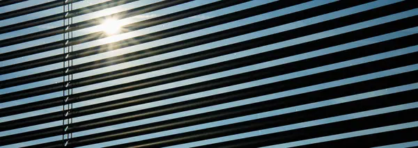 Blinds on the window to protect from sunlight. Close up shot of modern jalousie. View of the sun\'s rays through wooden blinds