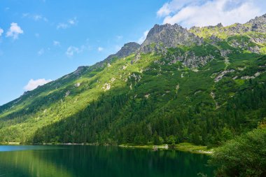 Yaz günü güzel göl kenarındaki dağların muhteşem manzarası. Polonya 'daki Tatra Ulusal Parkı. Beş Göl Vadisi 'ndeki Morskie Oko ya da Sea Eye Gölü' nün panoramik manzarası