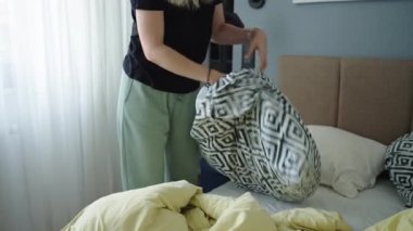 Odada çarşaf değiştiren kadın. Yatak odasında yatak yapan bir kadın. Rutin işler ve ev işleri.