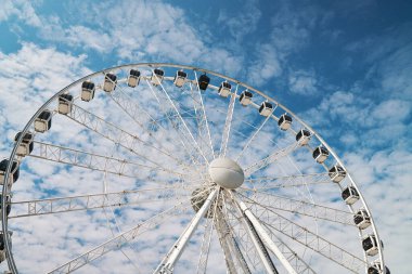 Dönme dolap mavi bulutlu gökyüzünün arka planında döner. Lunapark eğlencesi. Yaz tatili