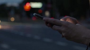 Kadın gece caddesinde akıllı telefon kullanıyor, sosyal medya okuyor ve internette geziniyor. Telefonunu elinde tutan kişi, hareket halindeki arabalarla gece sokağına bastırıyor. Çevrimiçi bağımlılık