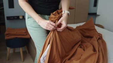 Odada çarşaf değiştiren kadın. Yatak odasında yatak yapan bir kadın. Rutin işler ve ev işleri.