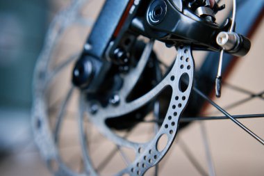 Bisikletin frenleme sisteminin bir parçası. Gri metal fren diski ve fren pedleri yol motorunda, kapatın..