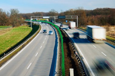 Yoğun otoyolun uzun pozu ve yolda sürüş arabalarının siluetleri. Otobanda trafik, hareket bulanık arabalar.