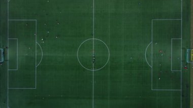 Yeşil sahada oynayan çocukların hava görüntüsü. Küçük stadyumdaki futbolcuların en iyi manzarası. Çocuklar futbol oynuyor.