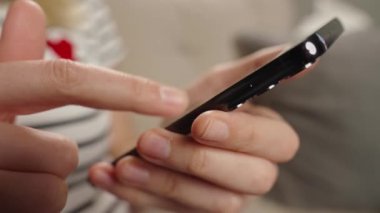 Ekranda sosyal medya görüntüsü olan akıllı telefonu rastgele kullanan kişi dijital içerikli bir müdahale öneriyor. Evde cep telefonu kullanan bir kadın