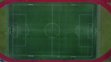 Yeşil sahada oynayan çocukların hava görüntüsü. Küçük stadyumdaki futbolcuların en iyi manzarası. Çocuklar futbol oynuyor.