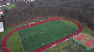 Koşu bandı ve futbol sahası olan stadyumun havadan görünüşü. Çocuklar parkın yakınındaki küçük bir taşra kasabasında sahada futbol oynarlar.