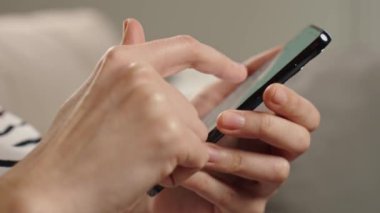 Ekranda sosyal medya görüntüsü olan akıllı telefonu rastgele kullanan kişi dijital içerikli bir müdahale öneriyor. Evde cep telefonu kullanan bir kadın