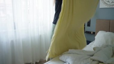 Odada çarşaf değiştiren kadın. Yatak odasında yatak yapan bir kadın. Rutin işler ve ev işleri.