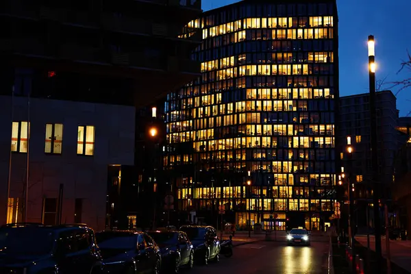 Office building lights up the evening with windows glowing in the dusk, showcasing urban work life after hours