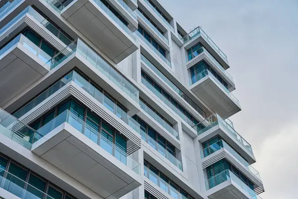 Şehirde bulutlu gökyüzüne karşı çağdaş binalar, balkonları ve cam pencereleri olan modern mimari yapılar..