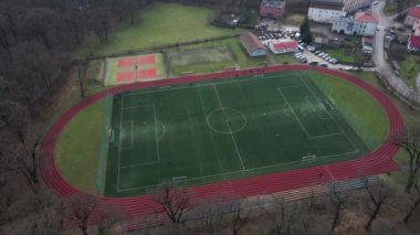 Koşu bandı ve futbol sahası olan stadyumun havadan görünüşü. Çocuklar parkın yakınındaki küçük bir taşra kasabasında sahada futbol oynarlar.