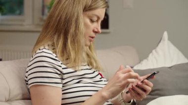 Ekranda sosyal medya görüntüsü olan akıllı telefonu rastgele kullanan kişi dijital içerikli bir müdahale öneriyor. Evde cep telefonu kullanan bir kadın