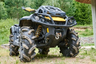 Büyük dört tekerli bir ATV aracı yeşil çimlerin üzerine park edilmiş. Off-road için dörtlü bisiklet