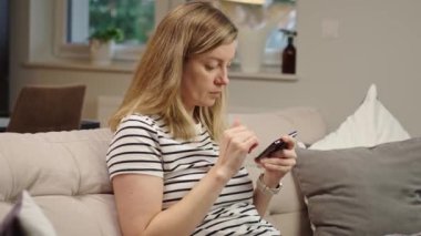 Ekranda sosyal medya görüntüsü olan akıllı telefonu rastgele kullanan kişi dijital içerikli bir müdahale öneriyor. Evde cep telefonu kullanan bir kadın