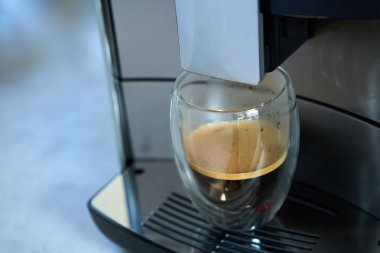 Sabah taze espresso. Kahve makinesi, cam bardakta taze demlenmiş kahve. Mutfak aletleri.