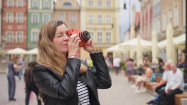 Kadın portakallı fotoğraf makinesiyle fotoğraf çekiyor. Turistler seyahat sırasında eski fotoğraf makineleriyle anılarını yakalıyorlar.
