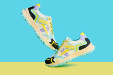 Parlak arka planda renkli aksanlı beyaz spor ayakkabılar renkli arka planda bir çift şık spor ayakkabısı. Mağaza reklamı için stüdyo fotoğrafı, yaratıcı minimalist stil.