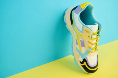 Parlak arka planda renkli aksanlı beyaz spor ayakkabı, renkli arka planda modaya uygun spor ayakkabı. Mağaza reklamı için stüdyo fotoğrafı, yaratıcı minimalist stil.