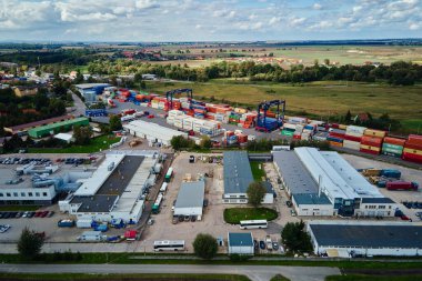 Terminaldeki MAERSK konteynırları, demiryolu platformundaki vinçleri, forkliftleri ve hava manzarası olan konteynırları boşaltıyorlar. Katy Wroclawskie, Polonya - 29 Eylül 2022