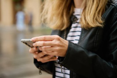 Şehir caddesinde akıllı telefon kullanan bir kadını yakından çek. Cep telefonu açık havada kadınların elinde.