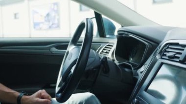 Otopark asistanının güneşli bir günde kendi arabasını park etmesi. Erkek sürücü içeride oturuyor ve direksiyona dokunmuyor. Gelişmiş otomotiv teknolojisine sahip araç