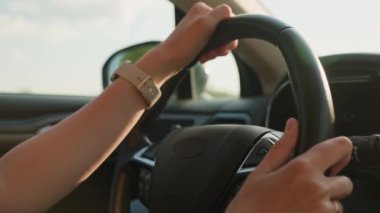 Direksiyondaki kadın sürücünün yakın görüntüsü. Gün batımında araba süren kadın. Yollarda ilerleyen modern aracın iç görünümü