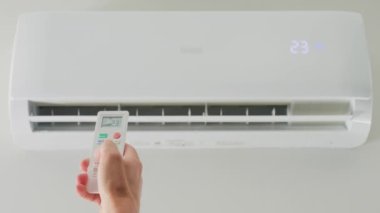 Klima sıcaklığını uzaktan kumandayla ayarlıyorum. Uzaktan kumandalı ve apartmandaki iklim sisteminde rahat sıcaklık ayarlı.