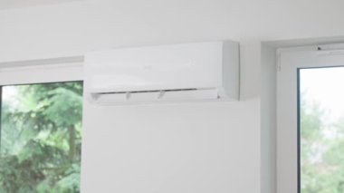 Modern apartmanın beyaz duvarına klima monte edilmiş. Oturma odasında rahat sıcaklık için soğutma sistemi