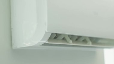 Modern apartmanın beyaz duvarına klima monte edilmiş. Oturma odasında rahat sıcaklık için soğutma sistemi