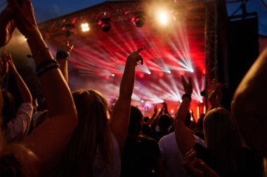 Sahnenin önündeki parlak spot ışıklarıyla konserdeki kalabalık siluetleri. İnsanlar bando konserinde canlı müzikten hoşlanırlar. Müzik festivalinde müzisyenler ve hayranlarla konser salonu
