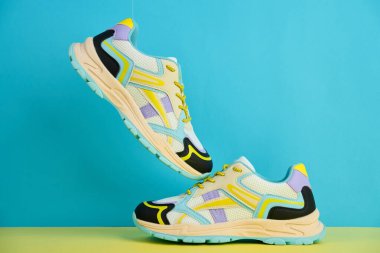 Parlak arka planda renkli aksanlı beyaz spor ayakkabılar renkli arka planda bir çift şık spor ayakkabısı. Mağaza reklamı için stüdyo fotoğrafı, yaratıcı minimalist stil.